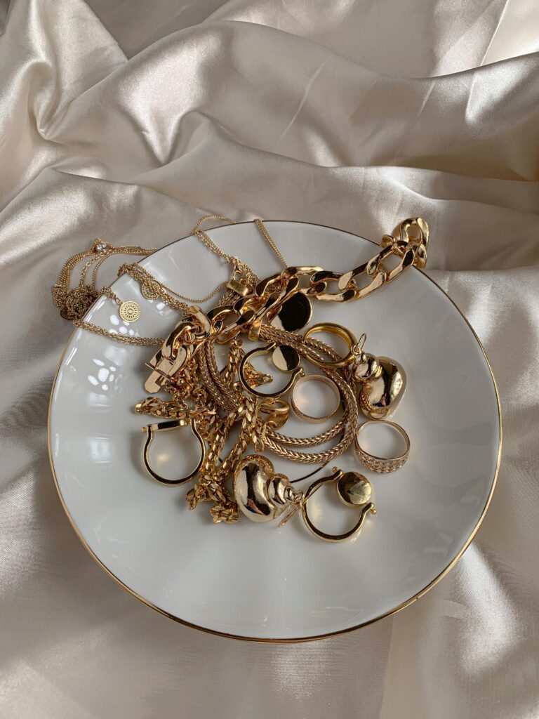 Stylish gold rings and necklaces elegantly displayed on a saucer with a silk background.costume jewelry store